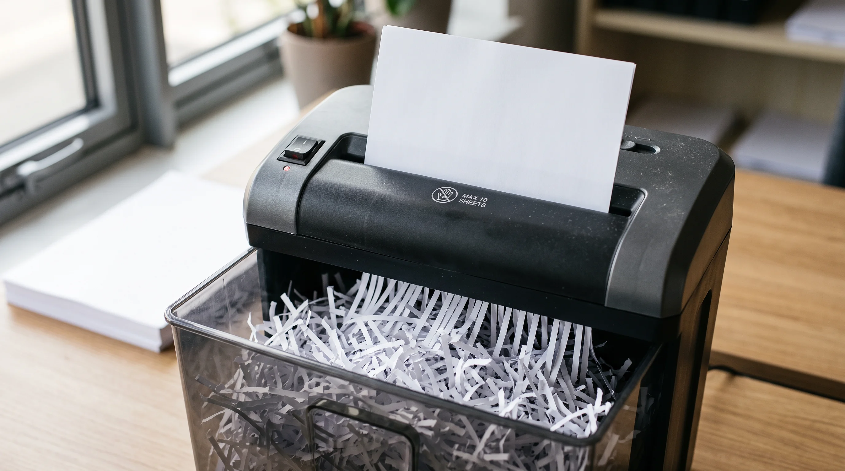 An unbranded cross-cut shredder with a drift of blank shredded strips — secure disposal, the quiet end of the data lifecycle done properly